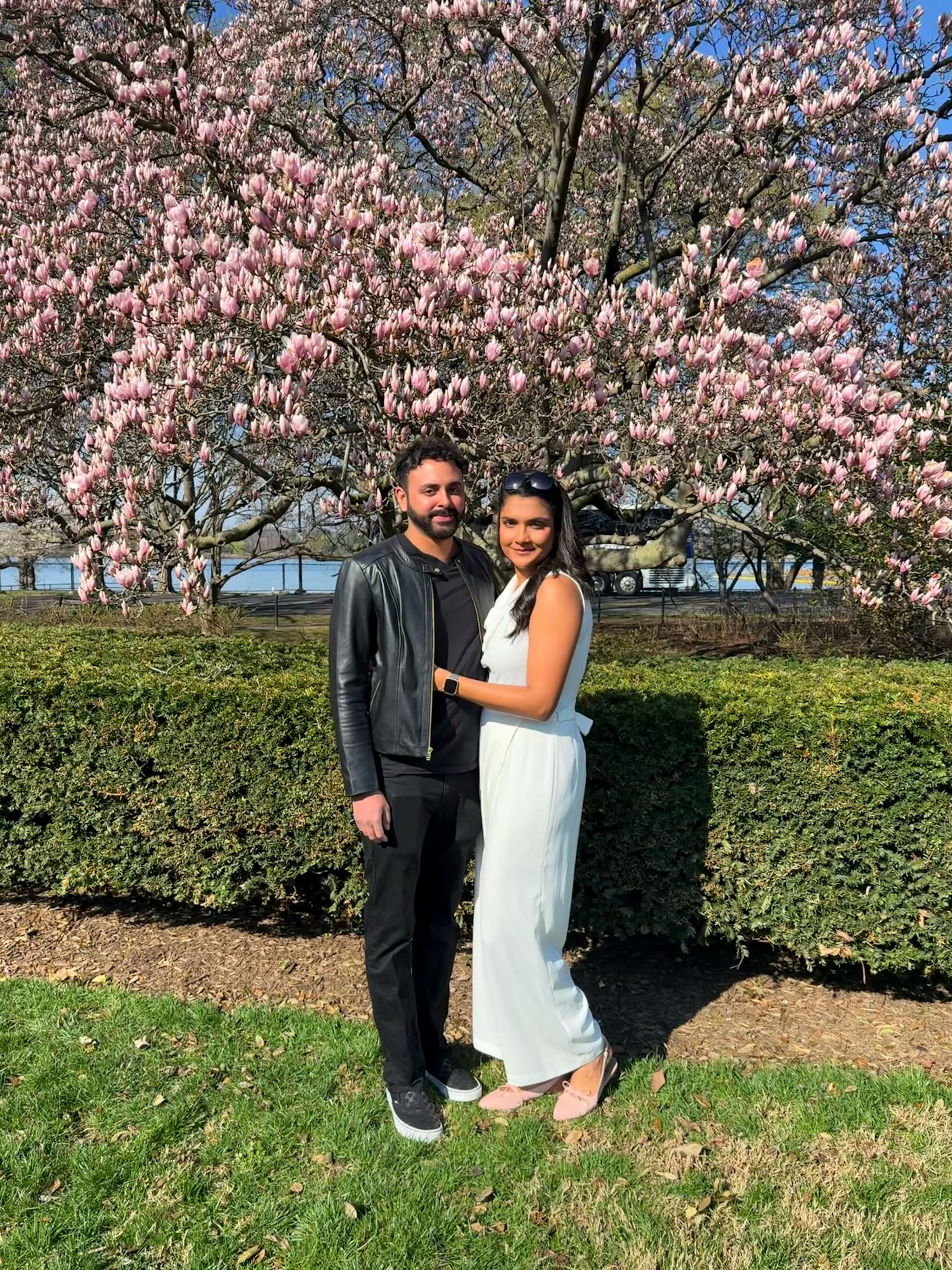 Kareena and Arvin standing beneath a blooming magnolia tree