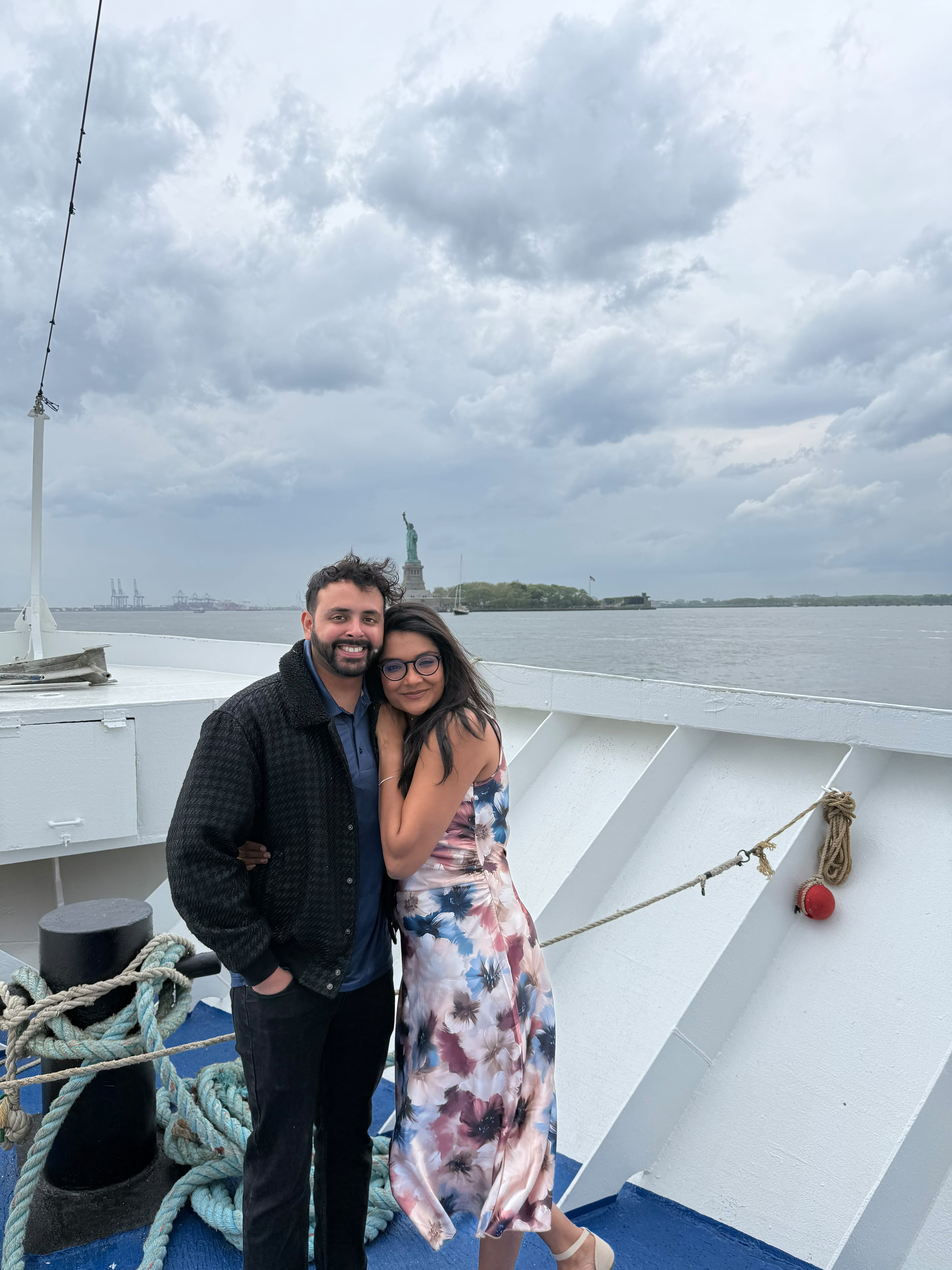 Kareena and Arvin embracing on a boat with the Statue of Liberty behind them